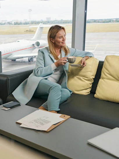 Airline passenger enjoying coffee in airport lounge with view of runway.