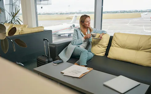 Airline passenger enjoying coffee in airport lounge with view of runway.