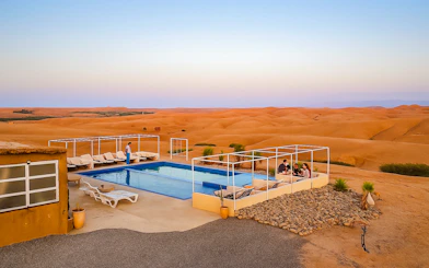 Poolside lounge area at Agafay Desert camp near Marrakech with desert landscape in the background.