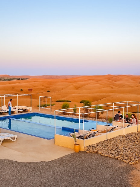 Poolside lounge area at Agafay Desert camp near Marrakech with desert landscape in the background.