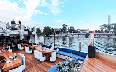 Nile Dahabiya cruise deck with dining tables and view of Cairo Tower.