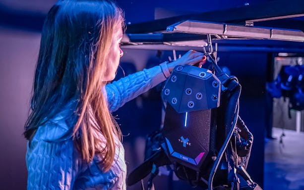 Person interacting with YULLBE PRO VR equipment in a dimly lit room.