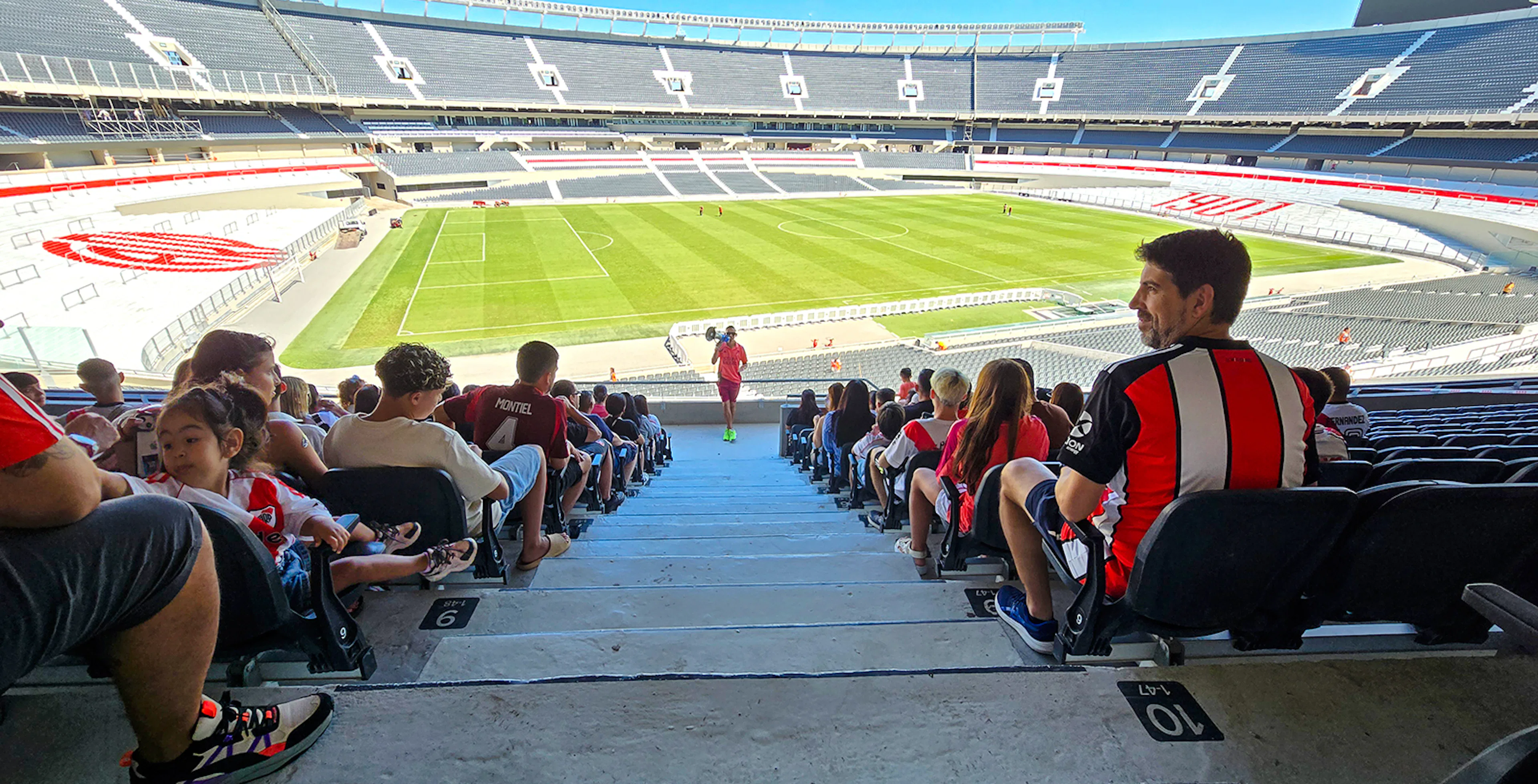 Guests seated at Estadio Monumental Stadium, home of River Plate football club, overlooking the field.