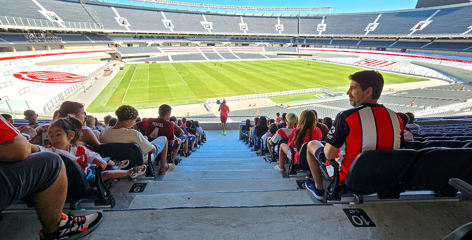 Guests seated at Estadio Monumental Stadium, home of River Plate football club, overlooking the field.