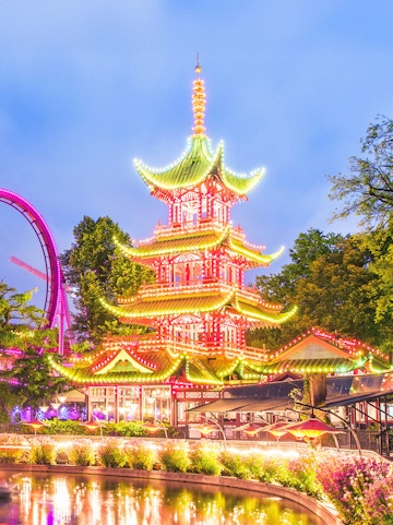 Tivoli Gardens pagoda illuminated at night with nearby rides, Copenhagen.