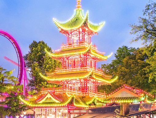 Tivoli Gardens pagoda illuminated at night with nearby rides, Copenhagen.