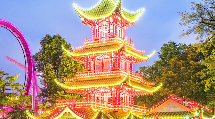 Tivoli Gardens pagoda illuminated at night with nearby rides, Copenhagen.