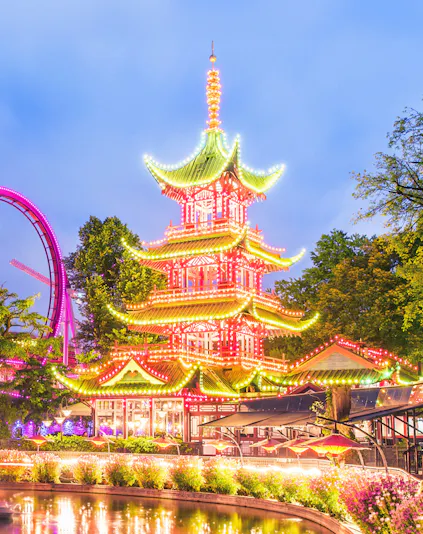 Tivoli Gardens pagoda illuminated at night with nearby rides, Copenhagen.