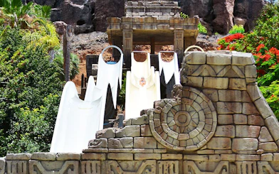 Visitors sliding down Kamikaze water slide at Aqualand Maspalomas, surrounded by lush greenery.
