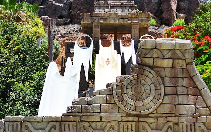 Visitors sliding down Kamikaze water slide at Aqualand Maspalomas, surrounded by lush greenery.