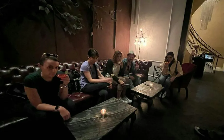 Group enjoying drinks in a dimly lit lounge, part of New York Lower East Side Murder Mystery tour.