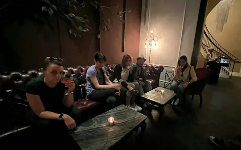 Group enjoying drinks in a dimly lit lounge, part of New York Lower East Side Murder Mystery tour.