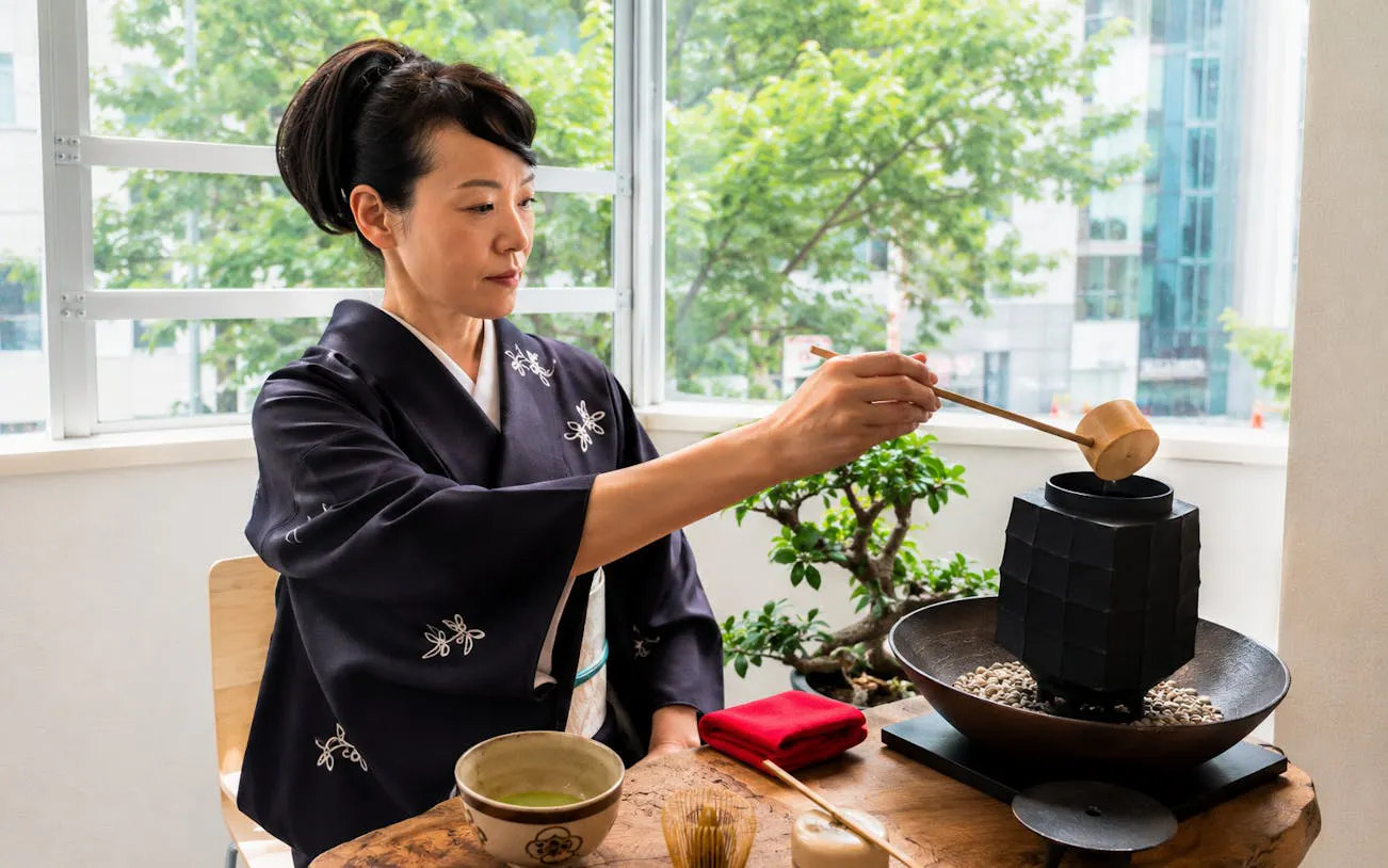 Woman in kimono preparing matcha tea during a workshop near Shibuya Crossing.