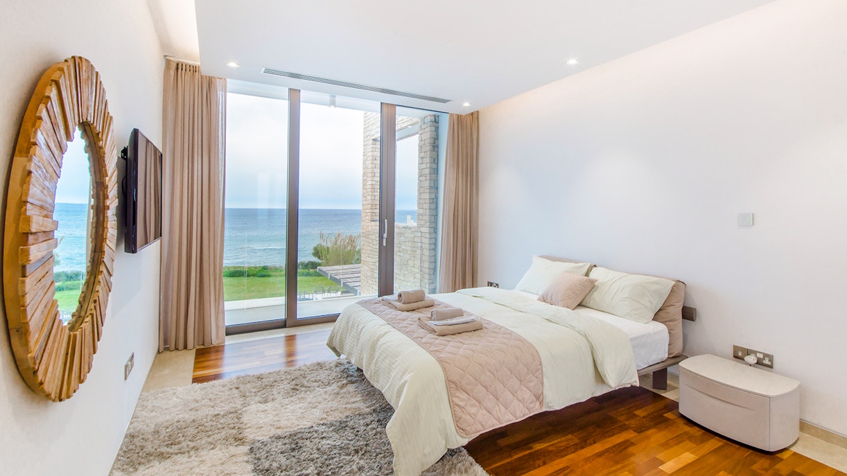 Ocean view hotel room with balcony overlooking the sea in a coastal city.