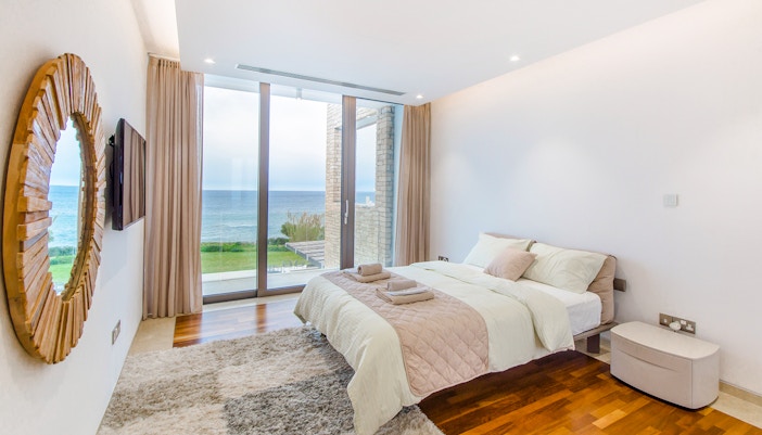 Ocean view hotel room with balcony overlooking the sea in a coastal city.