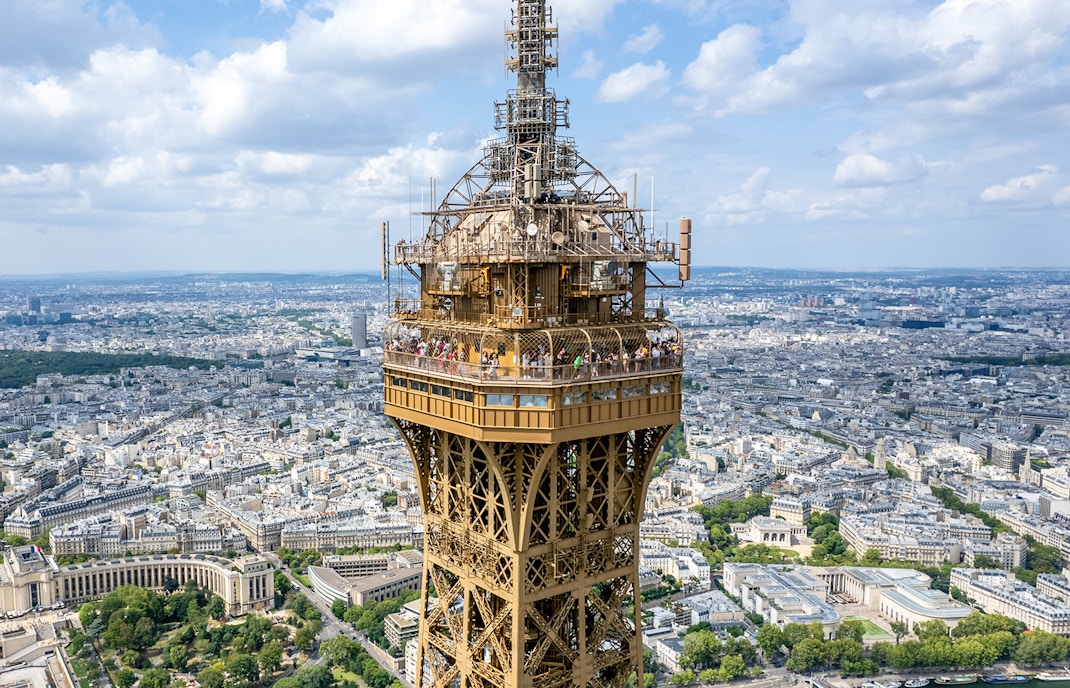 Eiffel Tower summit view with Paris cityscape in the background.