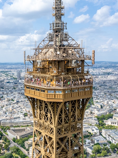 Eiffel Tower summit with Paris cityscape in the background.