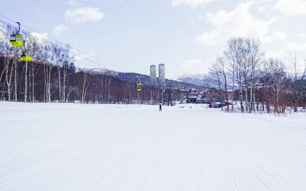 Skiers on snowy slopes with gondolas at Tomamu Ski Resort, Hokkaido, Japan.
