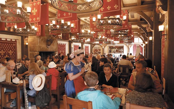Restaurant interior with diners and staff in period costumes, Puy Du Fou, France.