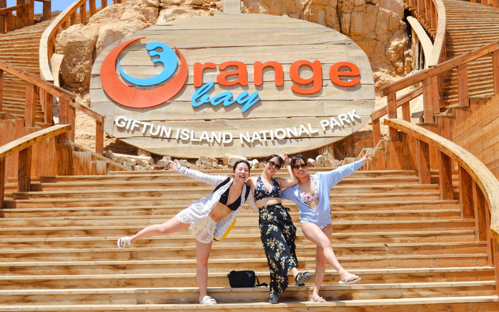 Visitors posing on wooden steps at Orange Bay, Giftun Island National Park.