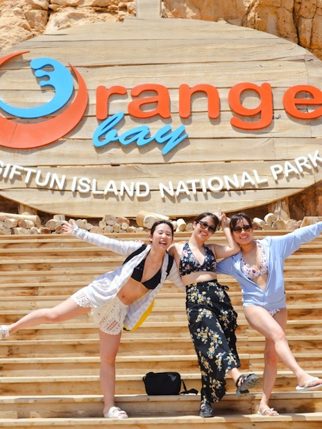 Visitors posing on wooden steps at Orange Bay, Giftun Island National Park.