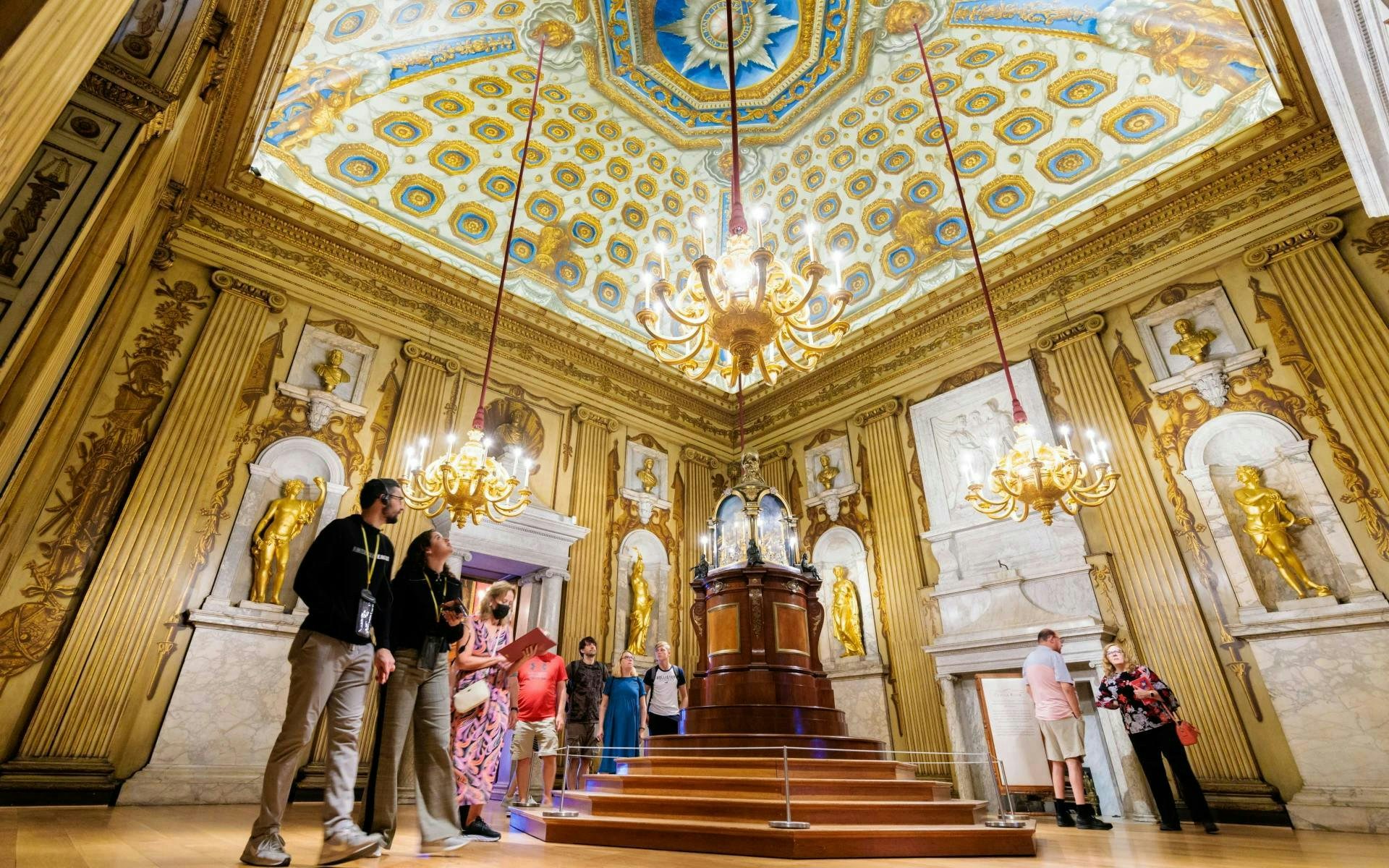 Cupola room with ornate ceiling and golden statues, visitors exploring the historic interior.