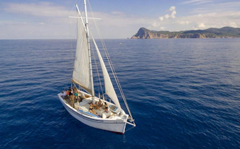 Tourists on a sailboat during a private sunset cruise near Ibiza coastline.