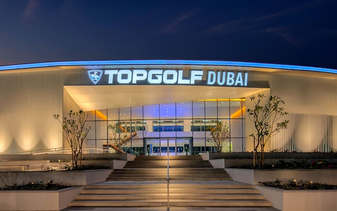 Topgolf Dubai entrance illuminated at night, showcasing modern architecture.