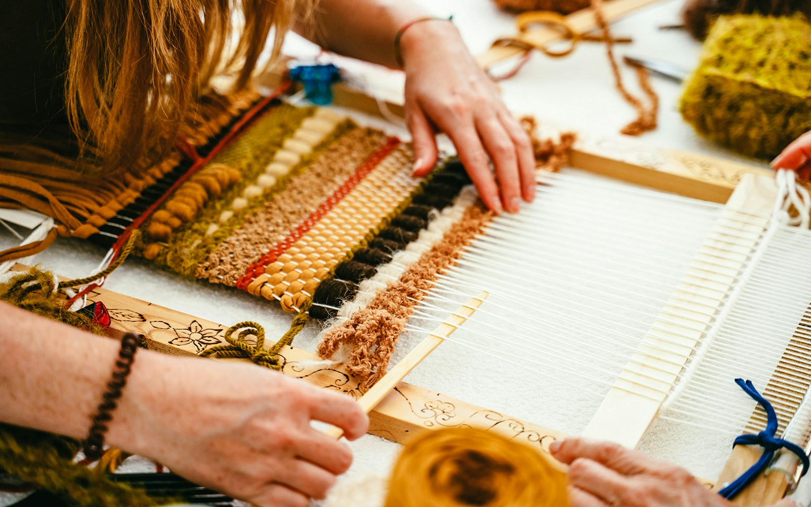 Hands weaving colorful fabric on a loom in Arachova, Greece.