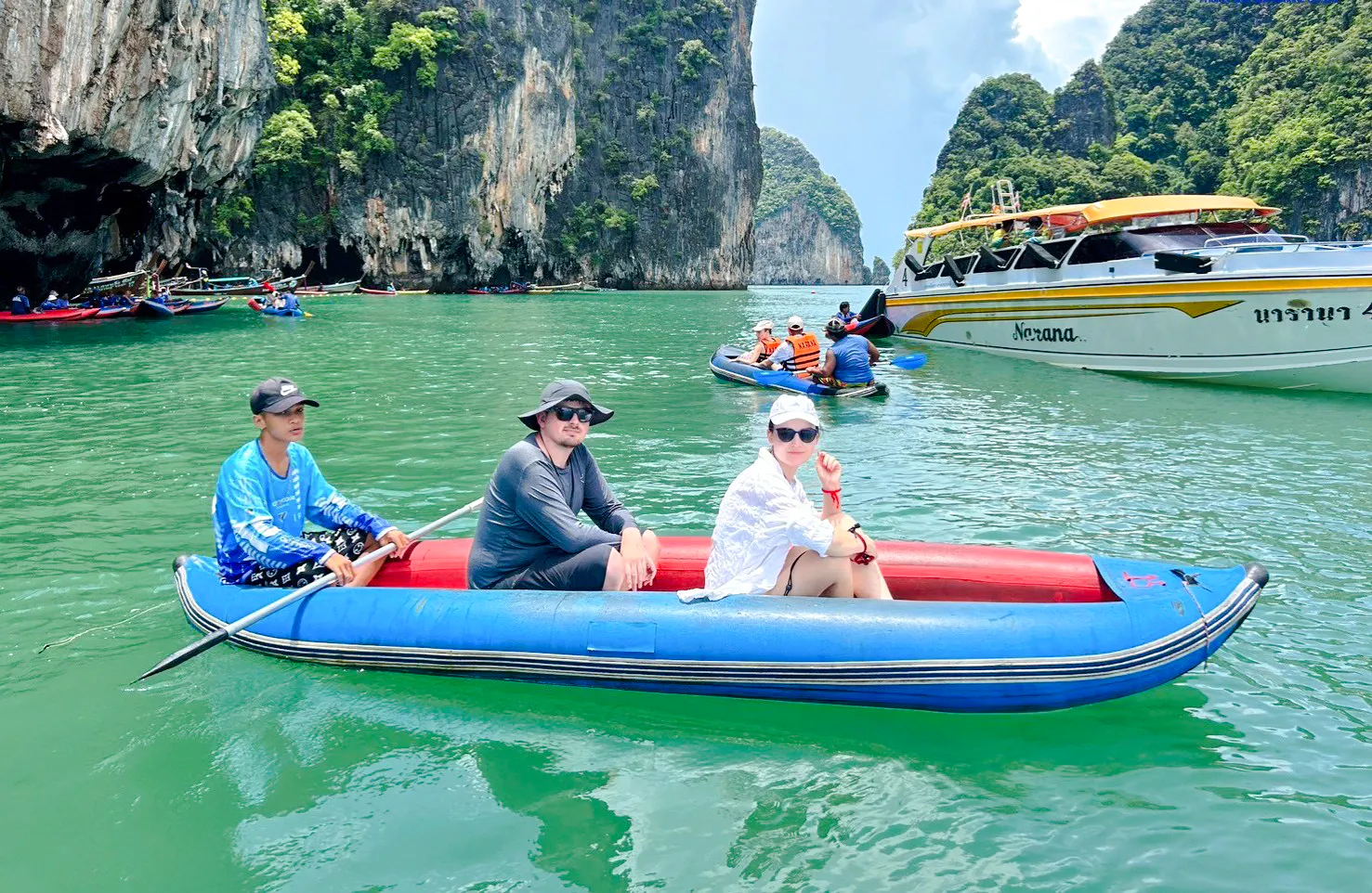 Tourists in a canoe exploring Phang Nga Bay with limestone cliffs, Phuket.
