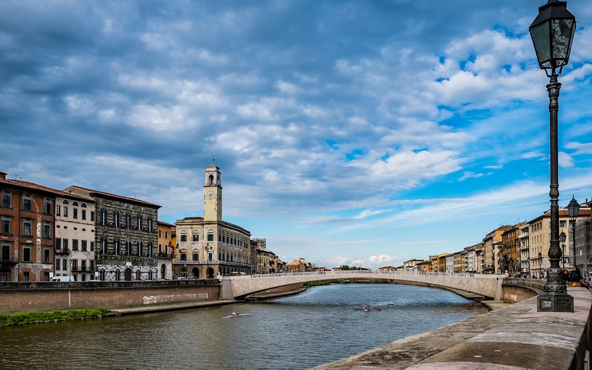 River Arno with historic buildings and bridge in Pisa, Italy.