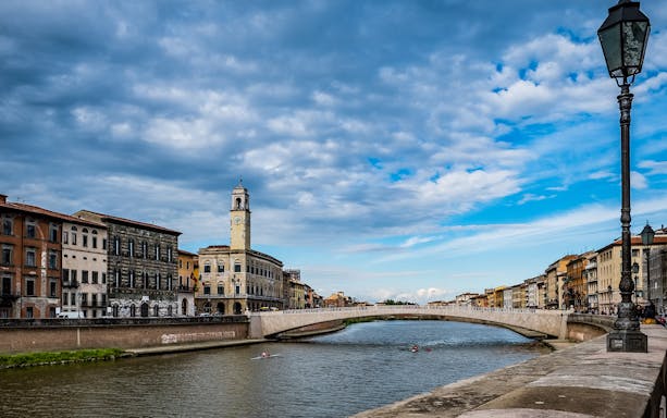 River Arno with historic buildings and bridge in Pisa, Italy.