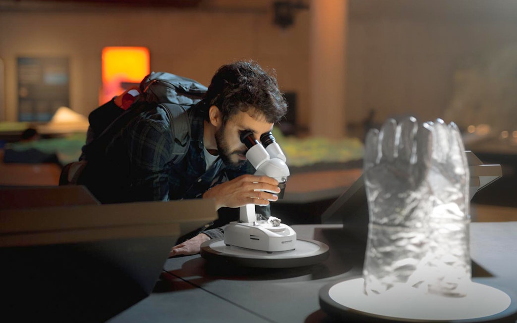 Visitor examining a sample with a microscope at Espai Crater exhibit.