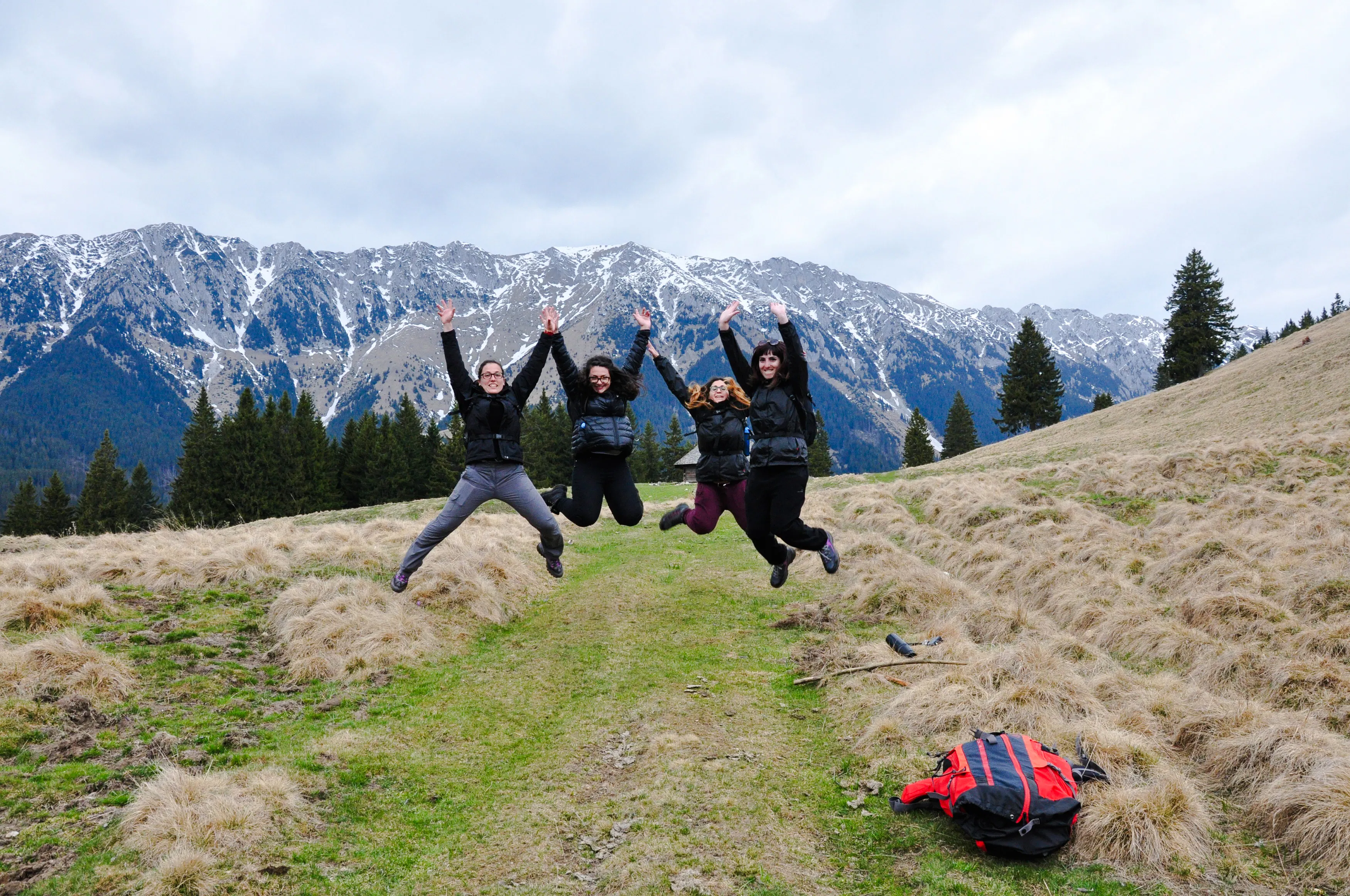 Group jumping on trail with Piatra Craiului mountains in background, Brasov trek.