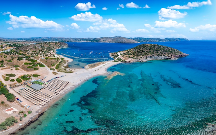 Aerial view of Agios Nikolaos beach, Saronida, Attica, with clear blue waters and sun loungers.