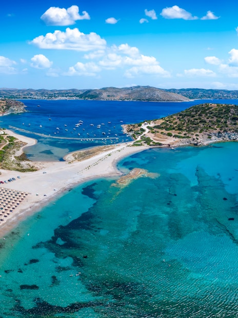 Aerial view of Agios Nikolaos beach, Saronida, Attica, with clear blue waters and sun loungers.