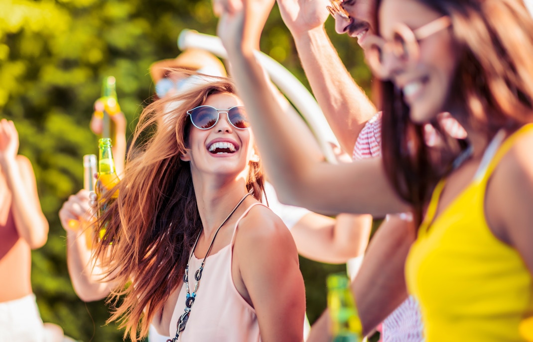 Friends enjoying a daytime outdoor party with drinks and laughter.