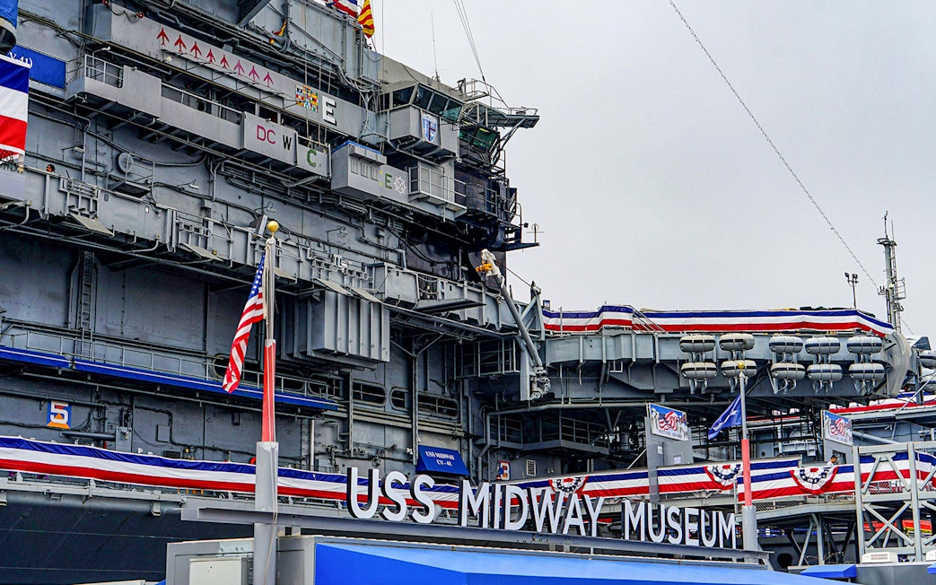 USS Midway Museum exterior with American flags and naval decorations.