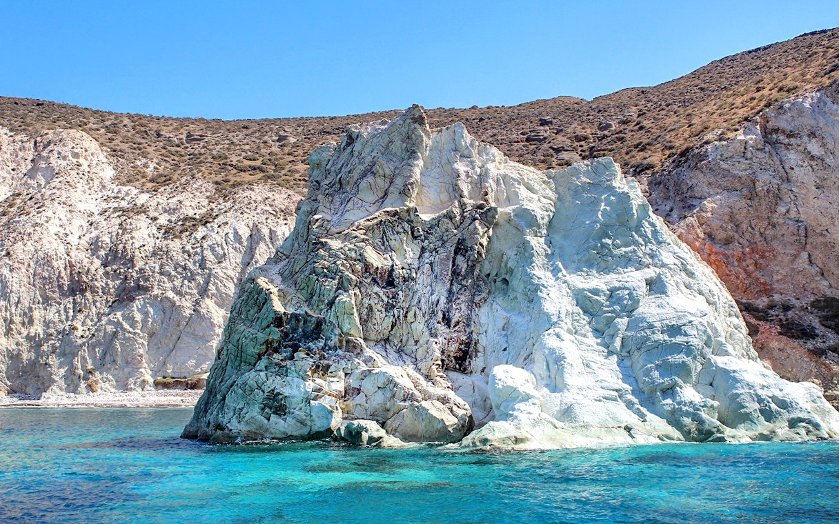 Rocky coastline with turquoise waters on Santorini Luxury Catamaran Cruise.