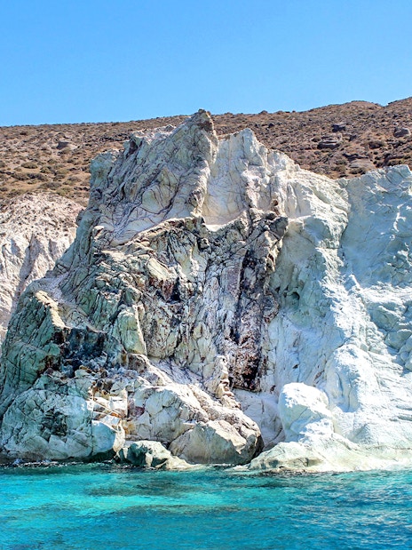 Rocky coastline with turquoise waters on Santorini Luxury Catamaran Cruise.