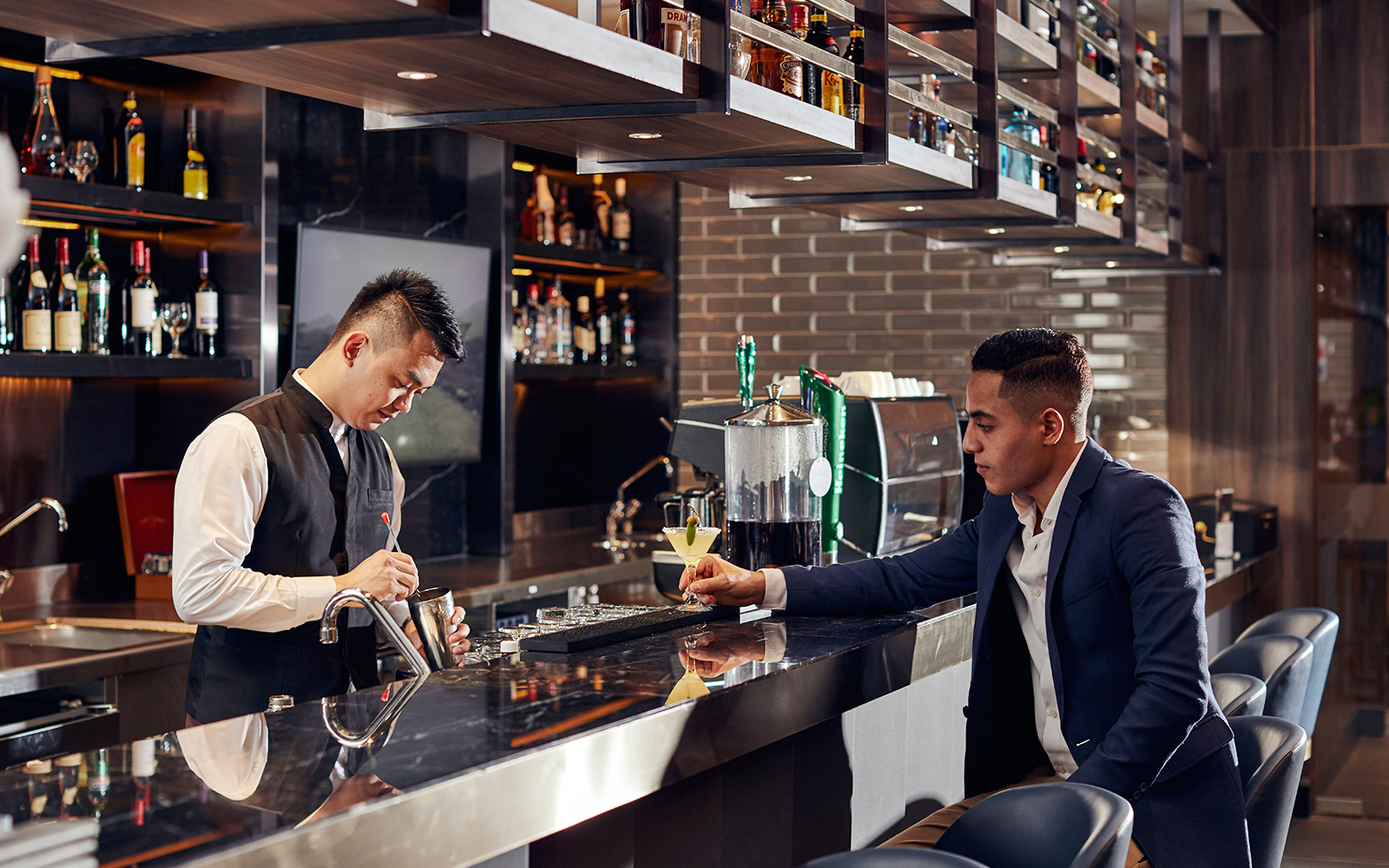 Bartender preparing a drink for a guest at Plaza Premium Lounge, Dubai International Airport.