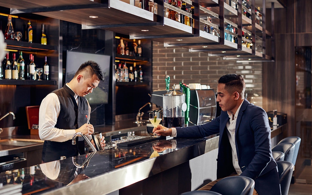 Bartender preparing a drink for a guest at Plaza Premium Lounge, Dubai International Airport.