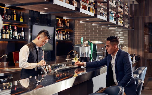 Bartender preparing a drink for a guest at Plaza Premium Lounge, Dubai International Airport.
