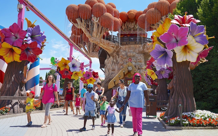 Families walking near colorful tree sculptures at Gardaland Park.