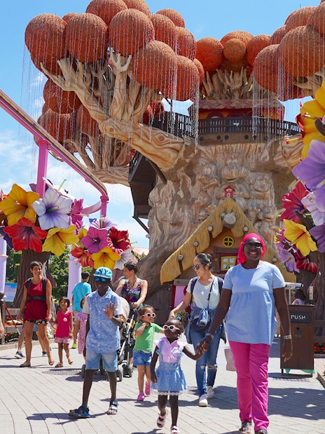 Families walking near colorful tree sculptures at Gardaland Park.