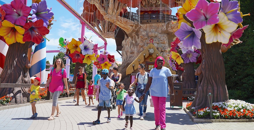 Families walking near colorful tree sculptures at Gardaland Park.