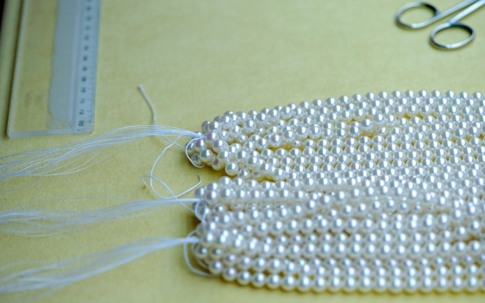 Pearl strands from a Mallorca pearl factory on a table with tools.
