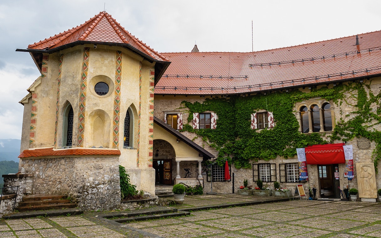 Inner courtyard of Bled Castle in Slovenia with ivy-covered walls and historic architecture.