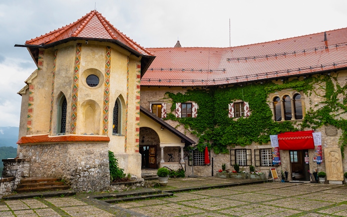 Inner courtyard of Bled Castle in Slovenia with ivy-covered walls and historic architecture.