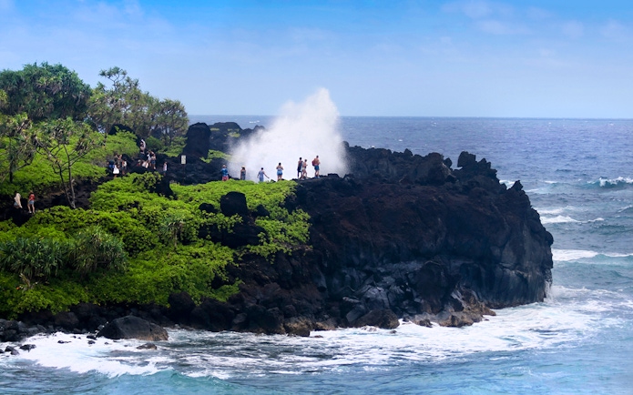 Visitors at a blowhole in Waianapanapa State Park, Maui, on the Road to Hana tour.
